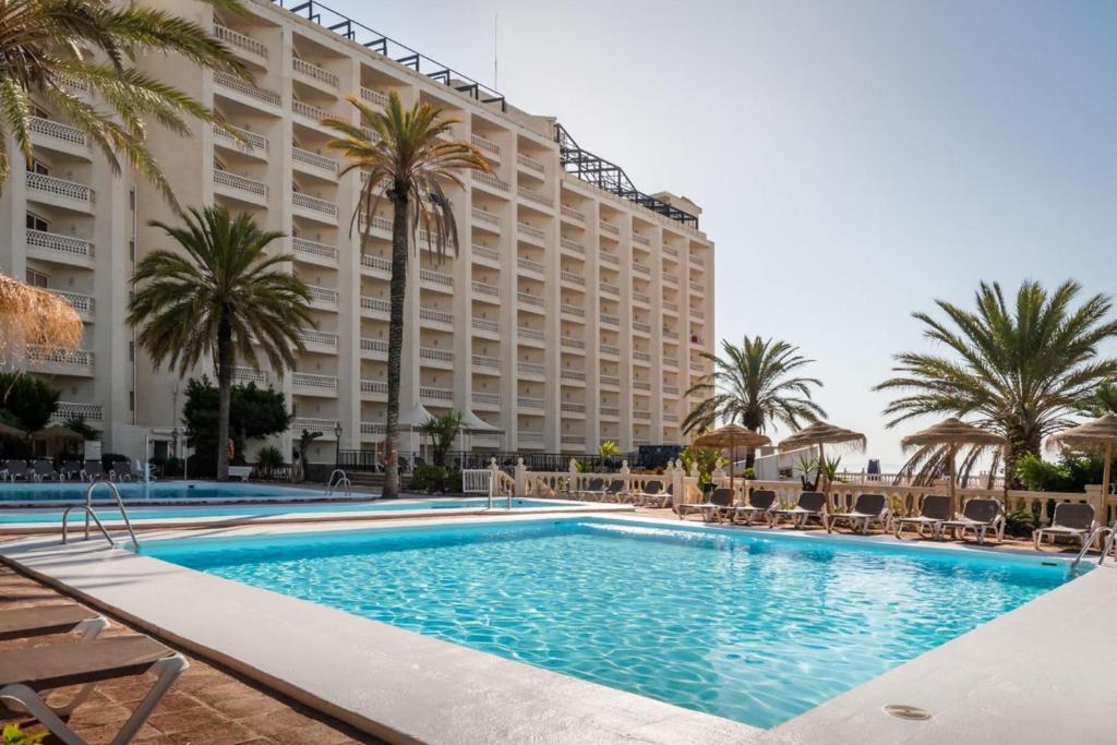 阿瓜杜尔塞Hotel Portomagno by ALEGRIA的棕榈树酒店前的游泳池