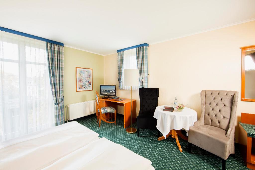 格赖夫斯瓦尔德科隆普林兹酒店的酒店客房配有一张床、一张桌子和一把椅子。
