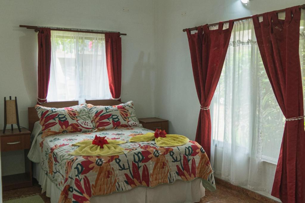 安加罗阿Hostal y Cabañas Aorangi的一间卧室配有床和两个带红色窗帘的窗户。