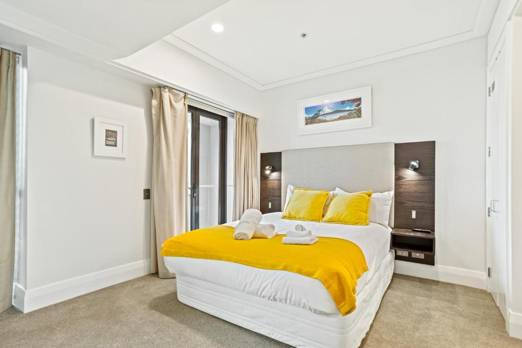 奥克兰Fabulous Corner Apartment w/ Dazzling Harbour View的一间卧室配有一张大床,床配有黄色的床单和黄色的枕头
