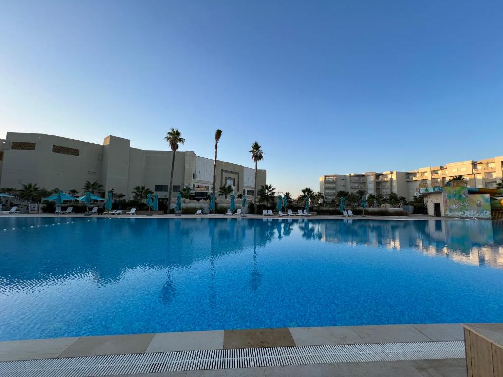 莫纳斯提尔Palm Lake Resort Folla Monastir/Sousse的一座种植了棕榈树和建筑的大型蓝色游泳池