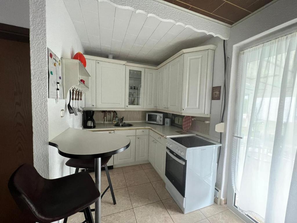 Haus Elli的厨房配有白色橱柜、桌子和水槽。