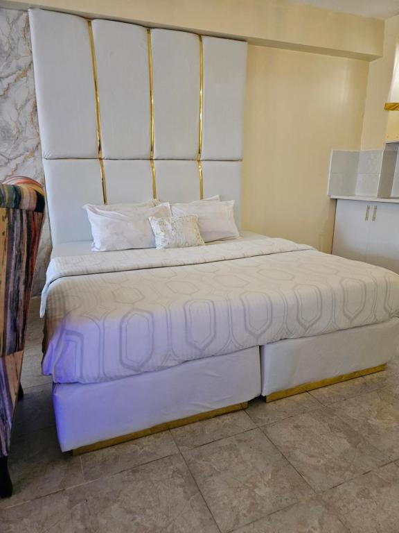 内罗毕Airport Studio Apartments-JKIA的卧室配有白色大床和白色枕头