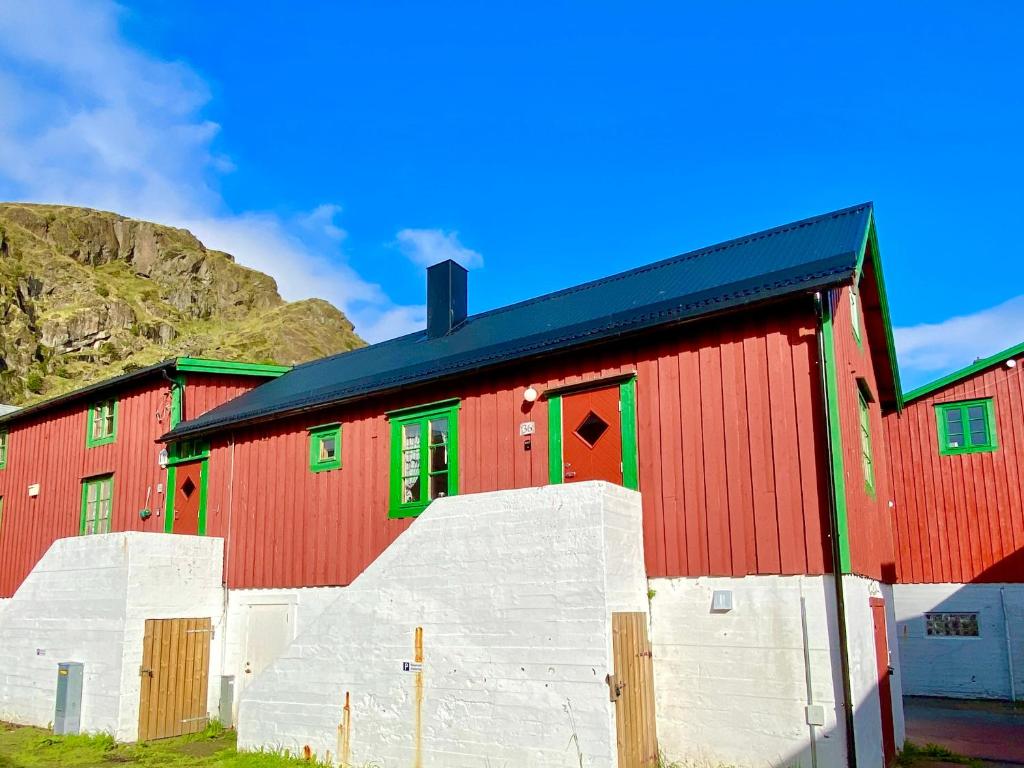斯塔姆松Charming Rorbu Stamsund Lofoten的红谷仓,设有绿色的窗户,享有山景