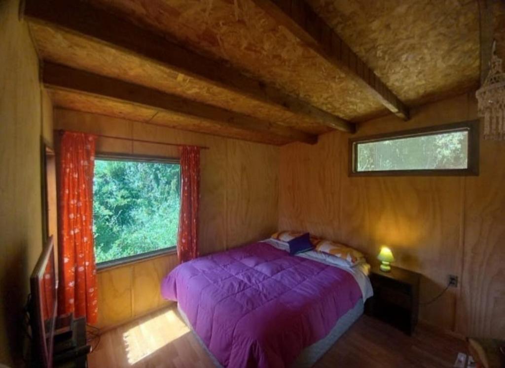 埃尔基斯科Cabañas Isla Neruda的一间卧室设有紫色的床和窗户