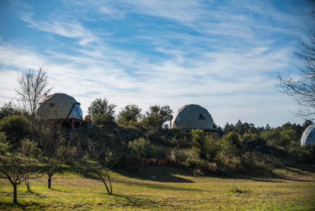 维拉卡洛斯帕兹GLAMPING TICA NATIVO的三个天文台坐在草地山顶上