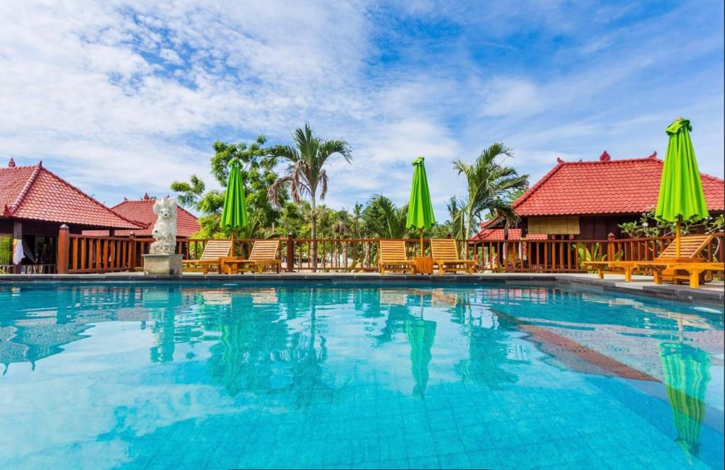 蓝梦岛Taman Sari Villa, Nusa Lembongan的度假村的游泳池,配有椅子和遮阳伞