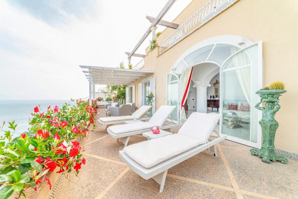 普莱伊亚诺Amalfi coast-Praiano Villa Cristina no steps的一个带白色椅子和鲜花的庭院和大海