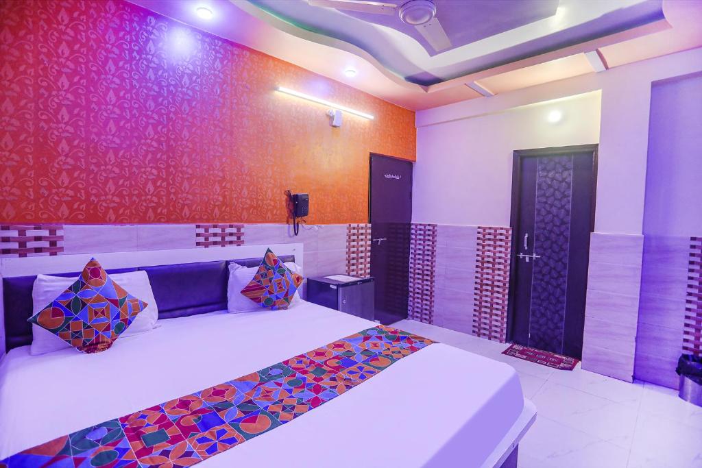 坎普尔FabExpress Kanha Dham的一间卧室配有一张带色彩缤纷枕头的大床