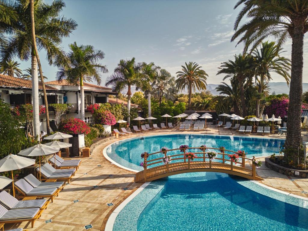 马斯帕洛马斯格朗卢悦君悦滨海大酒店的度假村的游泳池,带椅子和桥梁