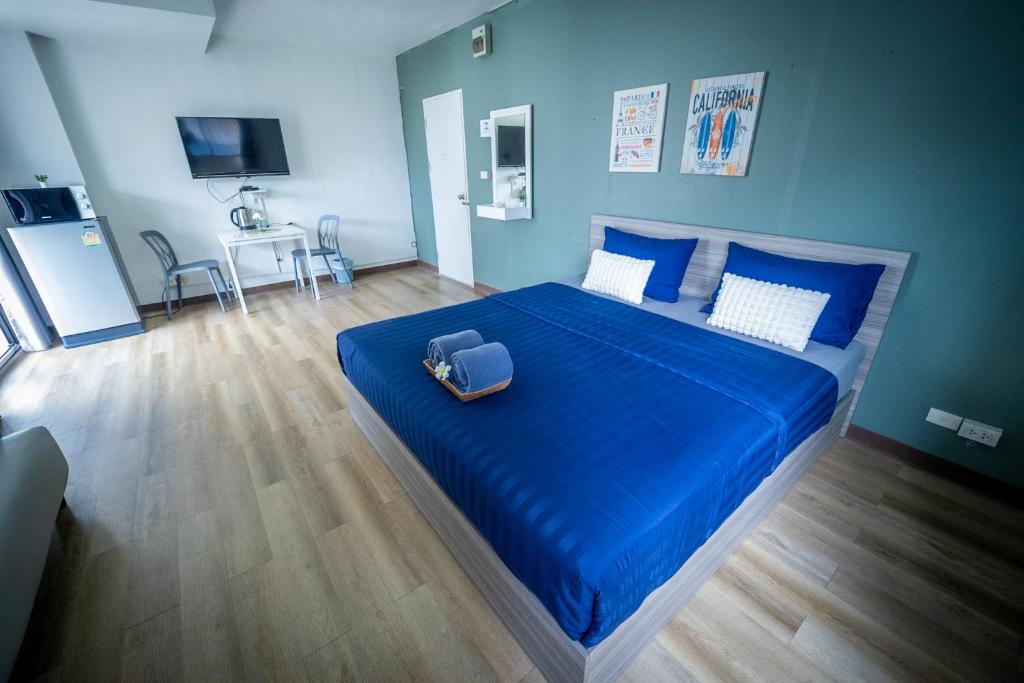 暖武里府Baansuay Rattanathibet Apartment的一间卧室配有一张带蓝色床单的床和手提箱。