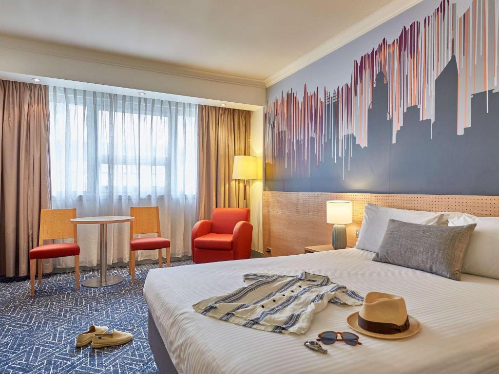 珀斯珀斯美居酒店的酒店客房,配有带帽子和太阳镜的床