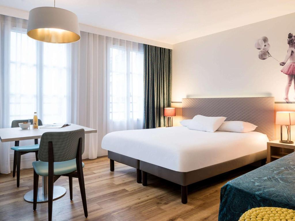 巴黎巴黎蒙马特爱达格公寓式酒店的配有一张床、一张桌子和一张桌子的酒店客房