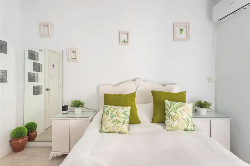耶克拉Wood&Stone Rooms的白色卧室配有白色床和绿色枕头
