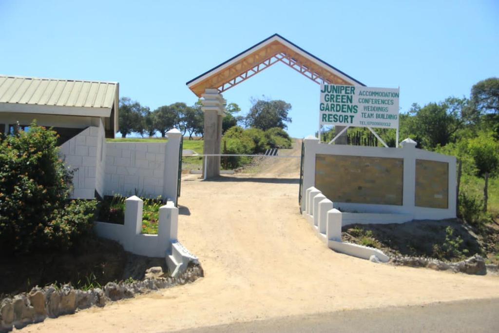 MweigaJuniper Green Gardens Resort.的建筑物前有标志的大门