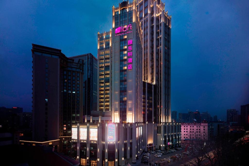 大连大连雅乐轩酒店的一座高大的建筑,上面有 ⁇ 虹灯标志