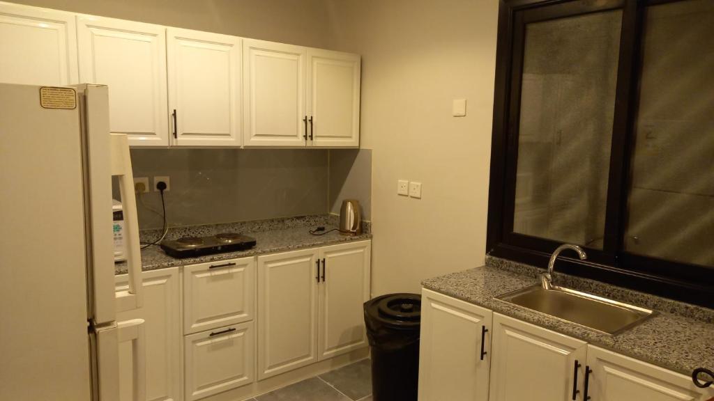 利雅德شقق بيت الوهد للشقق المخدومة的厨房配有白色橱柜和水槽