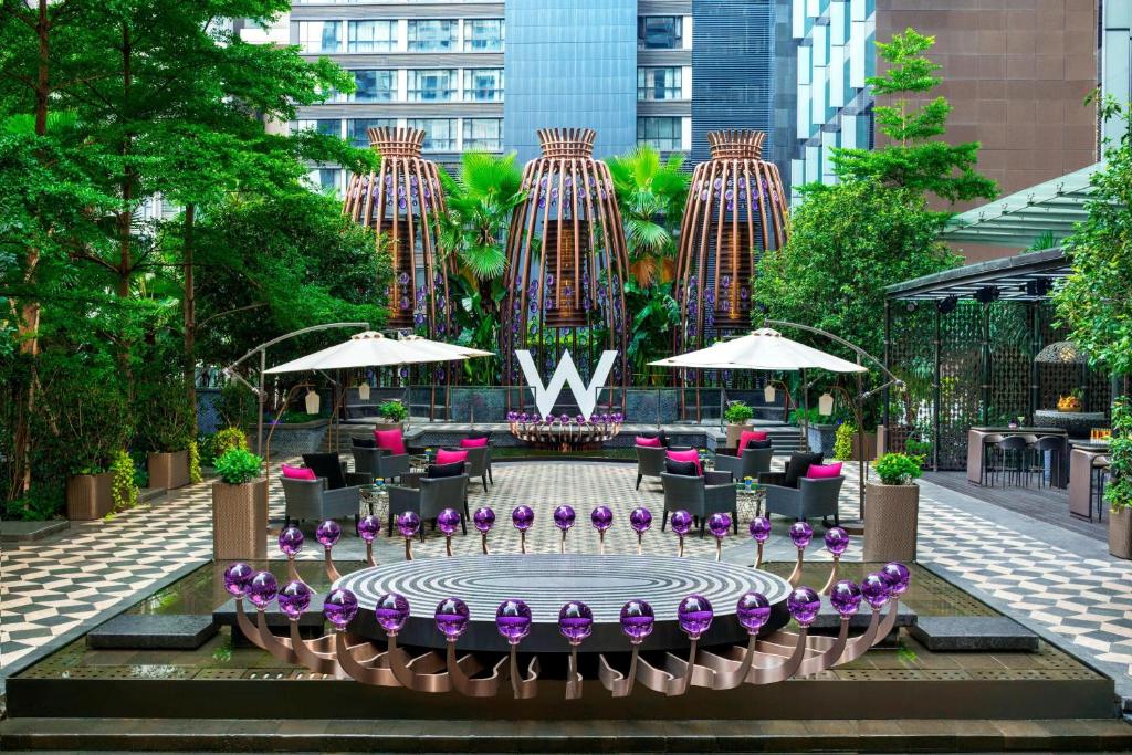 广州W Guangzhou的庭院设有喷泉,里面装有紫色的鲜花和遮阳伞