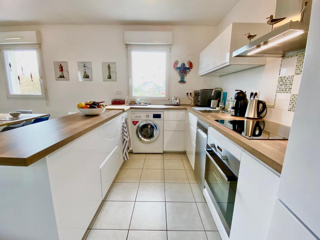 孔卡尔诺La Vigie的厨房配有白色橱柜、洗衣机和烘干机