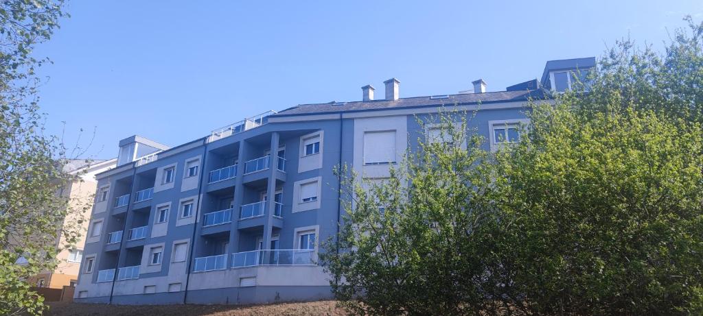 巴雷罗斯Atico en Barreiros 2 habitaciones的前面有树木的蓝色建筑