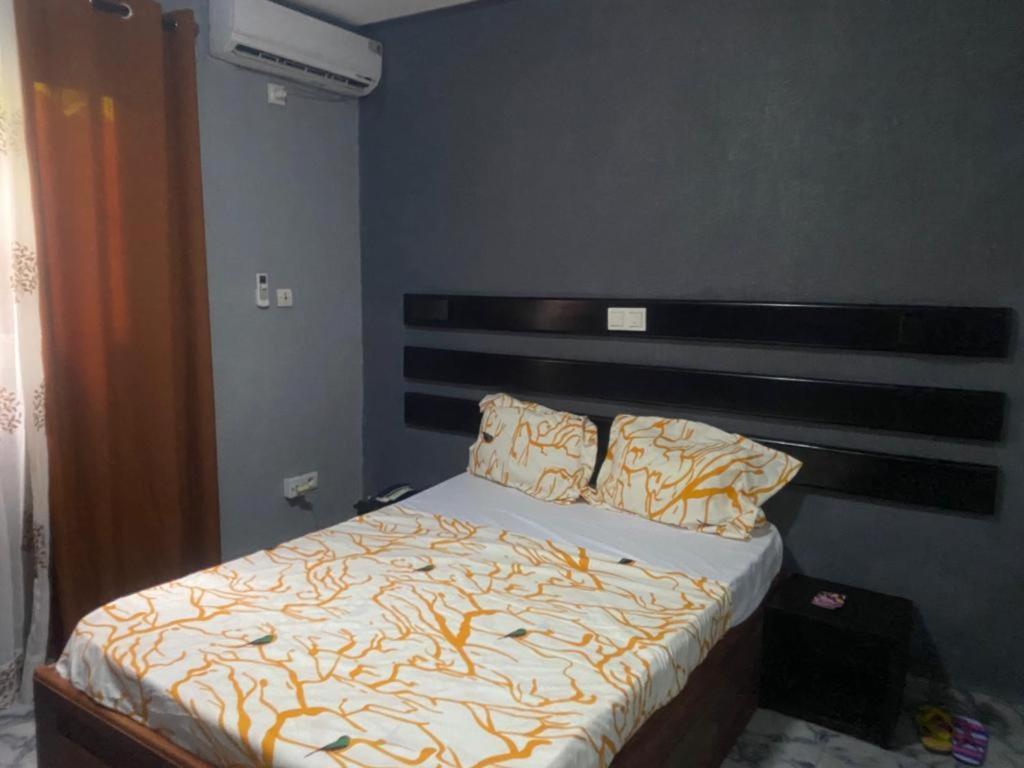 杜阿拉Sunrise Center Bonapriso 104的一间卧室配有一张带木制床头板的床