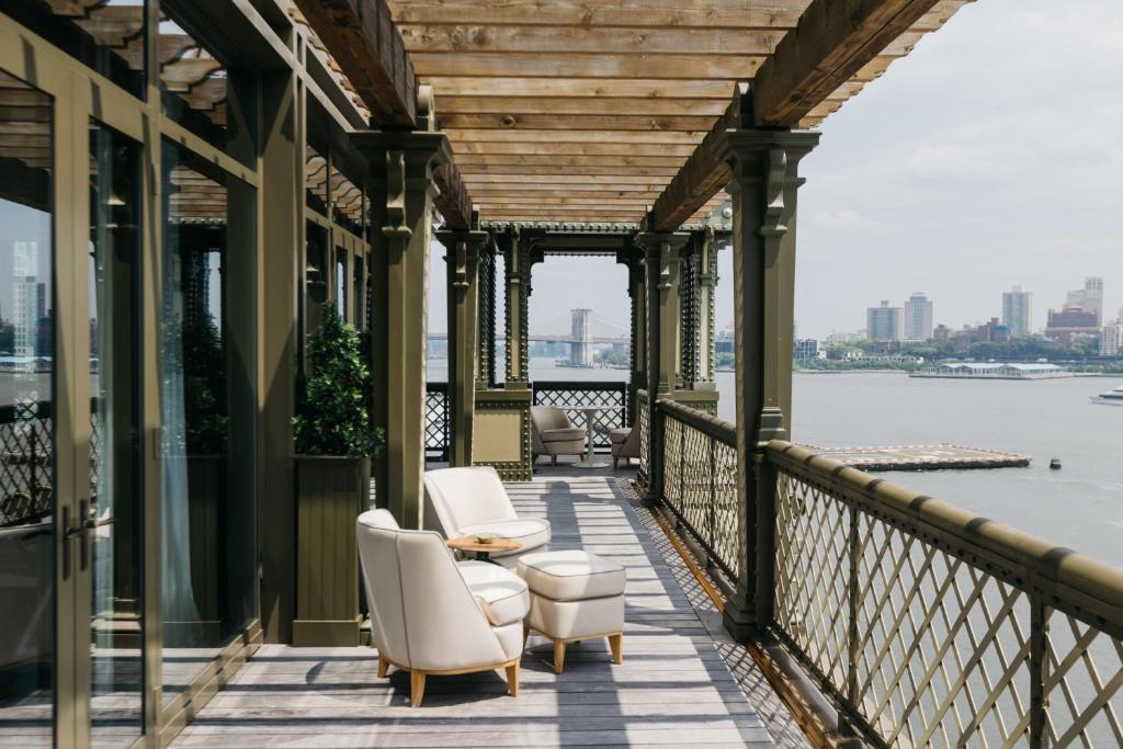 纽约Casa Cipriani New York的一个带椅子和桌子的屏蔽门廊,享有水景