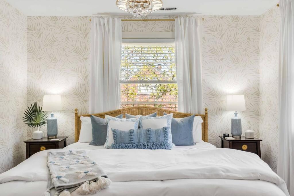 查尔斯顿The Grand Millennial in Downtown Charleston的一间卧室配有一张带蓝色枕头的床和一扇窗户。