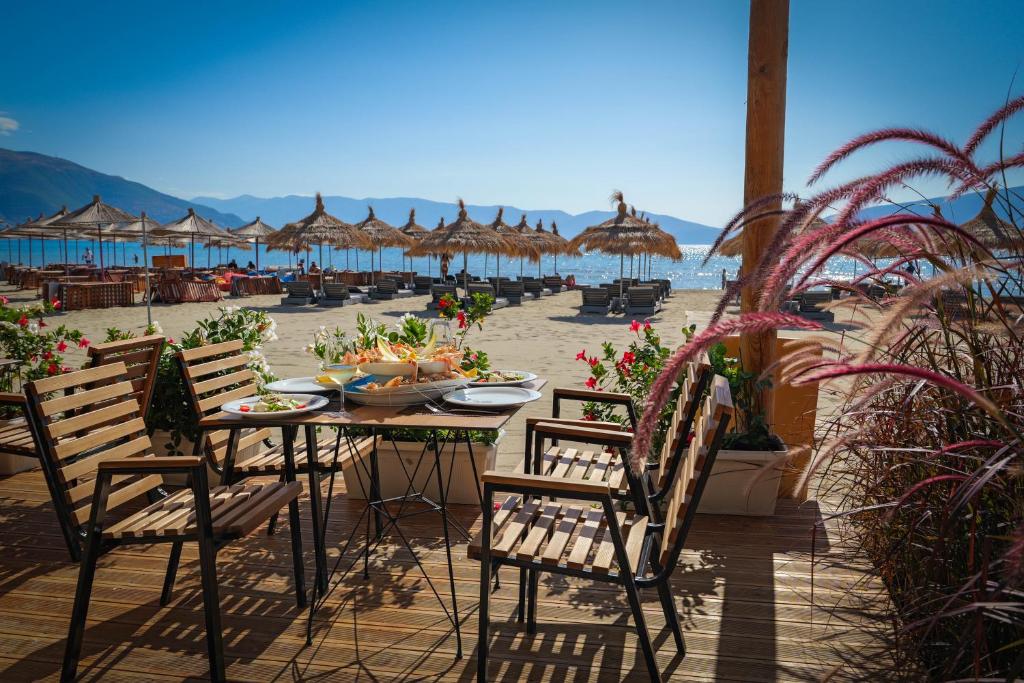 伏罗拉Sea & Sand Hotel的海滩上的桌椅和遮阳伞
