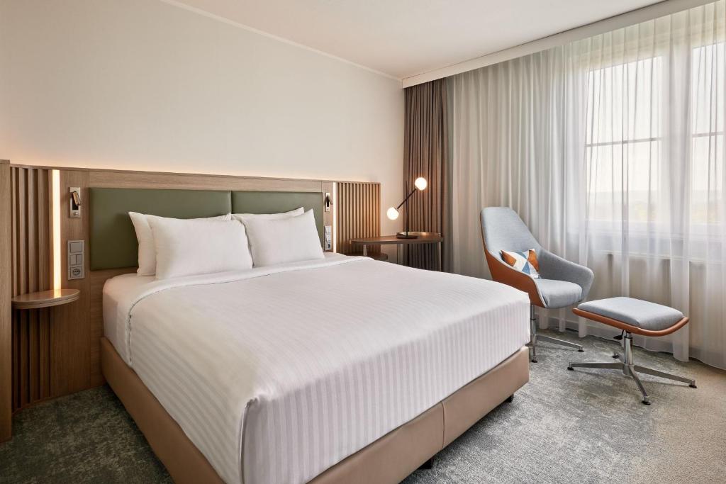 多特蒙德Courtyard by Marriott Dortmund的酒店客房带一张大床和一把椅子