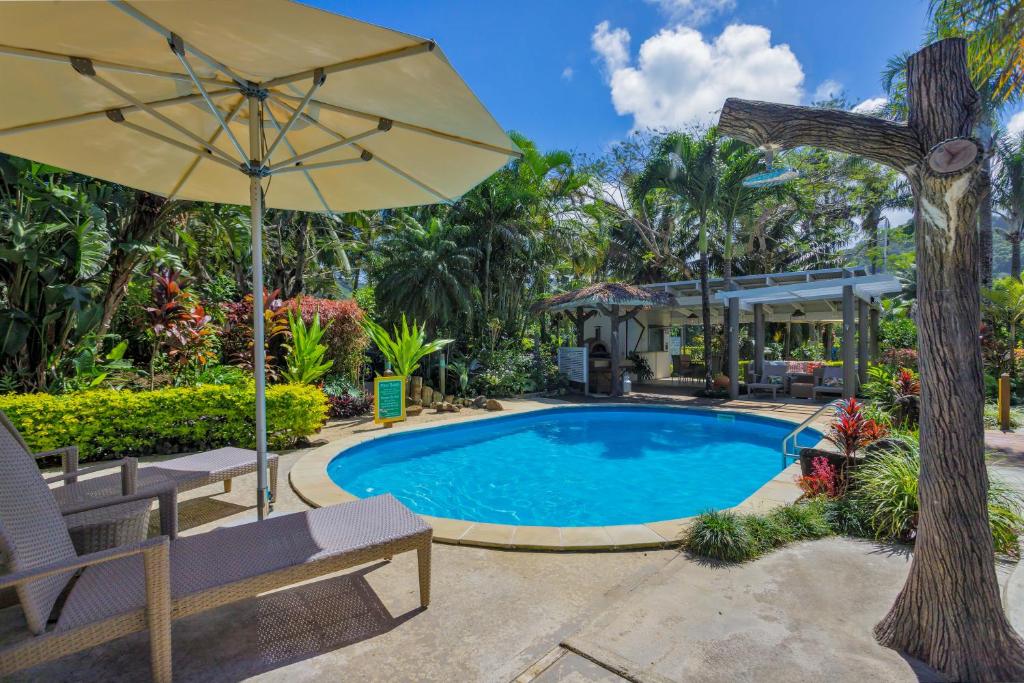 拉罗汤加Rarotonga Daydreamer Escape的一个带遮阳伞和长凳的游泳池