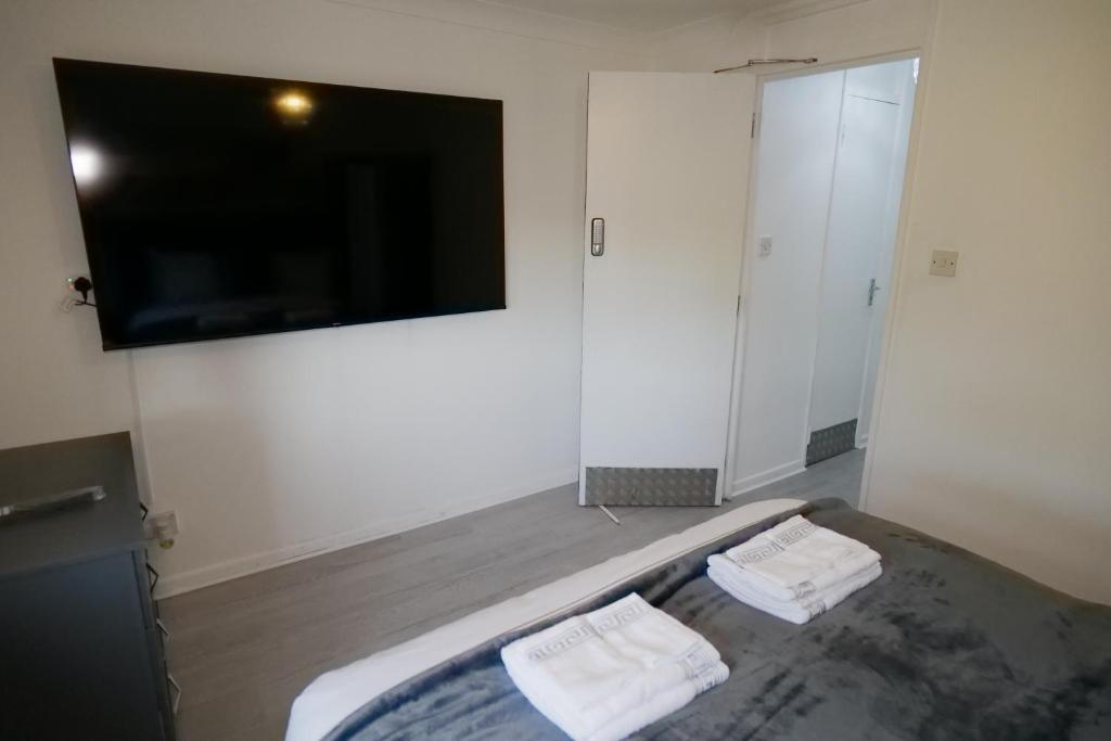 米尔顿凯恩斯Giomakay luxury Rooms Milton Keynes的一间卧室配有一张床和一台平面电视