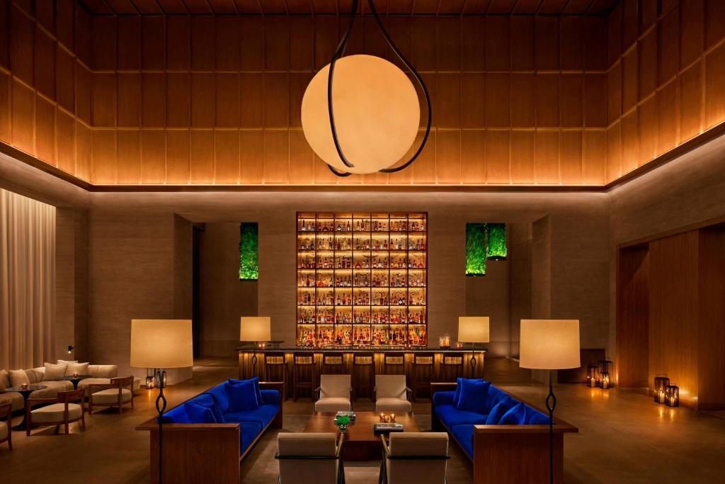 上海上海艾迪逊酒店的酒店大堂设有蓝色的沙发和一堵葡萄酒瓶