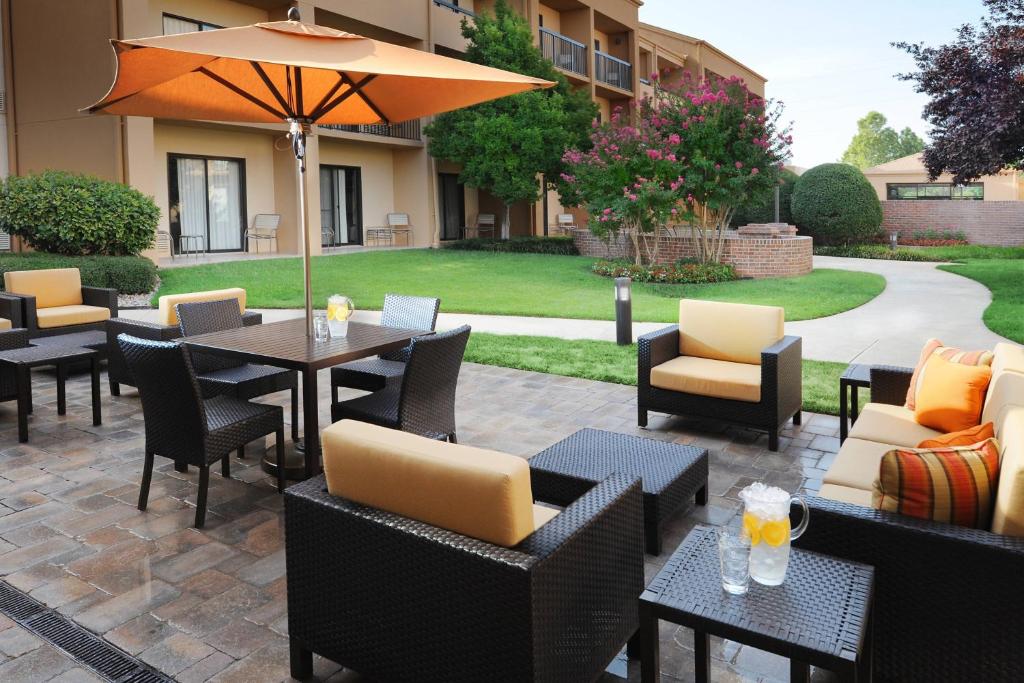 俄克拉何马城俄克拉荷马城机场万怡酒店的一个带桌椅和遮阳伞的庭院