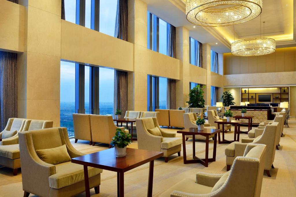 沈阳沈阳新都绿城喜来登酒店的酒店大堂设有桌椅和窗户。