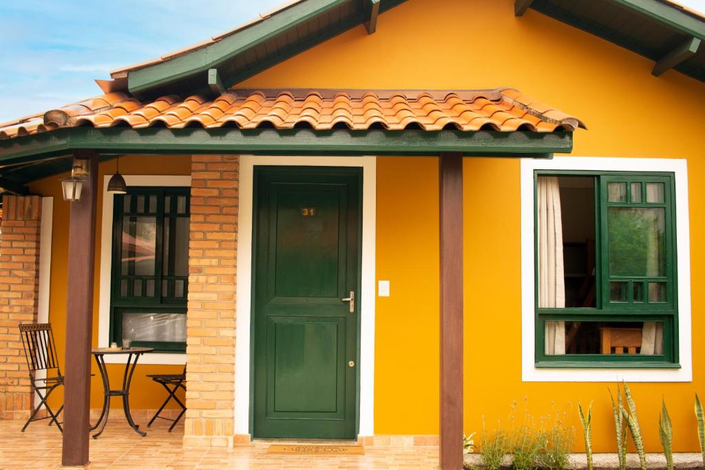 弗洛里亚诺波利斯Chalé 31的黄色的房子,设有绿色的门和桌子