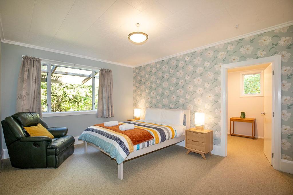 普纳凯基Cliffscapes的卧室配有床、椅子和窗户。