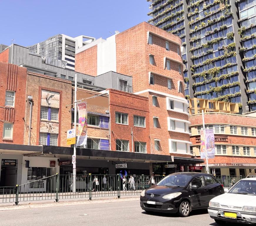悉尼Sydney RiseOn Hotel的两辆汽车停在大楼前的街道上