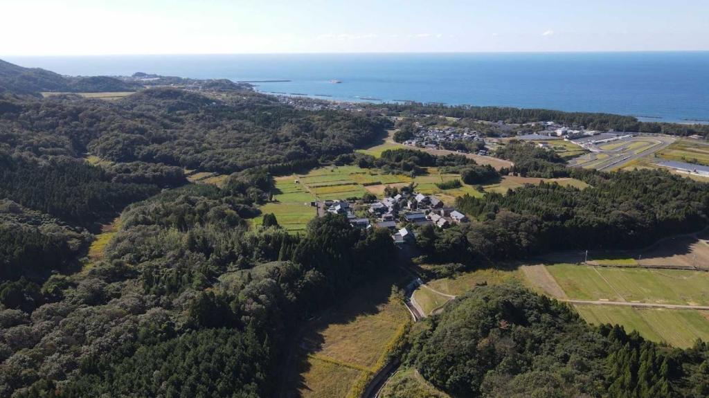 福井Auberge Fujii Fermier的大海旁山丘上房屋的空中景观