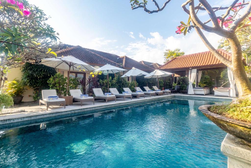 沙努尔爱丽莎别墅及套房度假村的度假村的游泳池,配有躺椅和遮阳伞