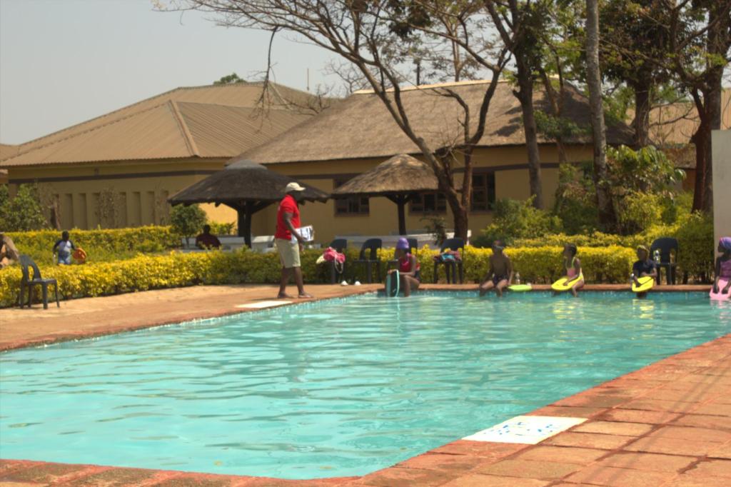 利隆圭Demera Motel的一群人站在游泳池周围
