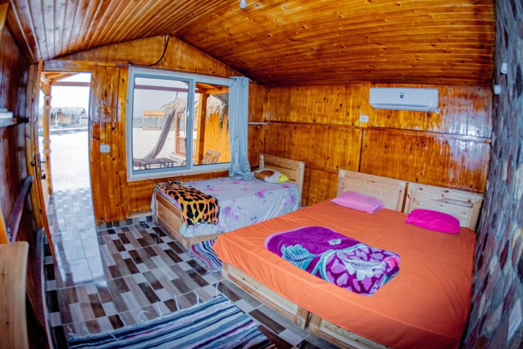 塔巴Yasmina Beach的小木屋内一间卧室,配有两张床