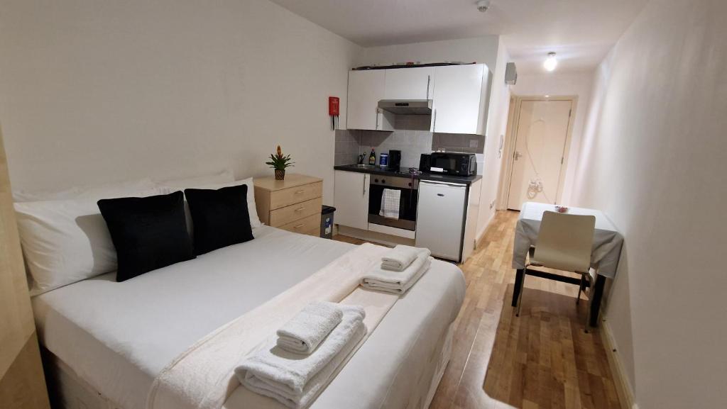 伦敦Compact living cosy studio flat in london的带厨房的小客房内的一张白色床