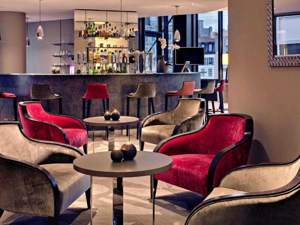 克莱蒙费朗克莱蒙费朗美居中心焦德广场酒店的一间设有红色桌椅的餐厅和一间酒吧
