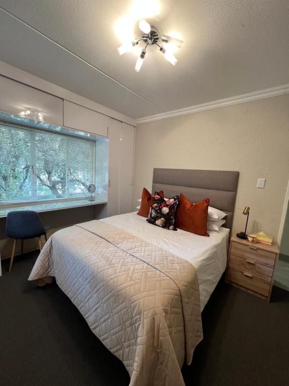 约翰内斯堡Tanelsa Apartment on West的一间卧室配有一张带吊扇和窗户的床。