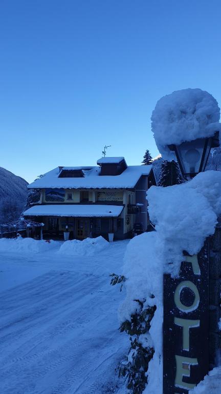 泰穆Hotel Veduta dell'Adamello的一座被雪覆盖的建筑,前面有标志