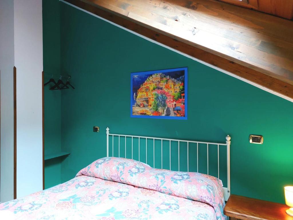 阿杰罗拉La Locanda del Pettirosso的一间卧室设有绿色的墙壁和一张带床罩的床