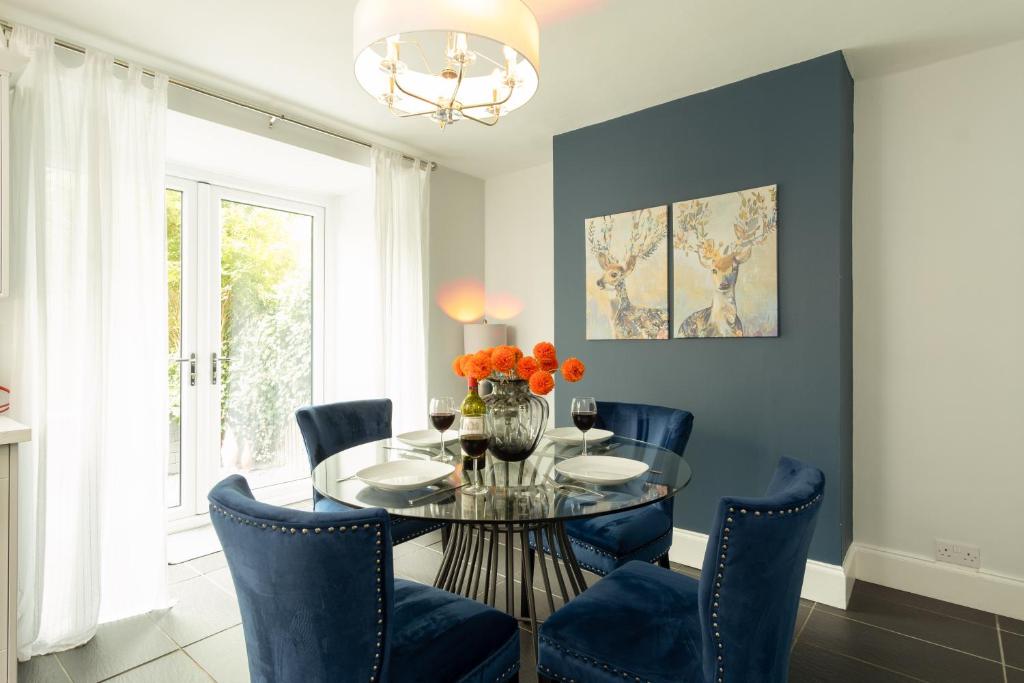 莱斯特Stratford House的一间设有玻璃桌和蓝色椅子的用餐室