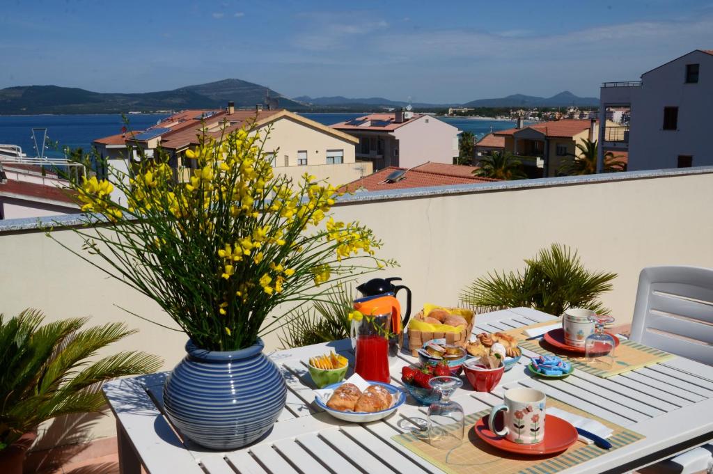 阿尔盖罗洛克多住宿加早餐酒店的阳台上的桌子上摆放着食物和花瓶