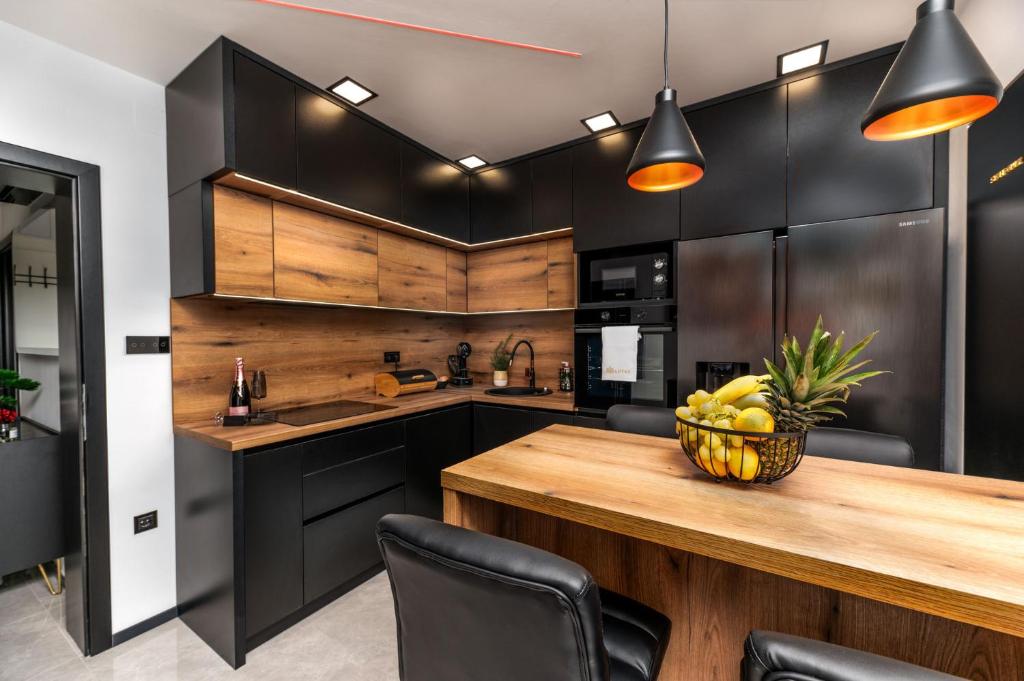 科普里夫尼察Lotus Wellness & spa apartman的厨房配有黑色橱柜和木桌