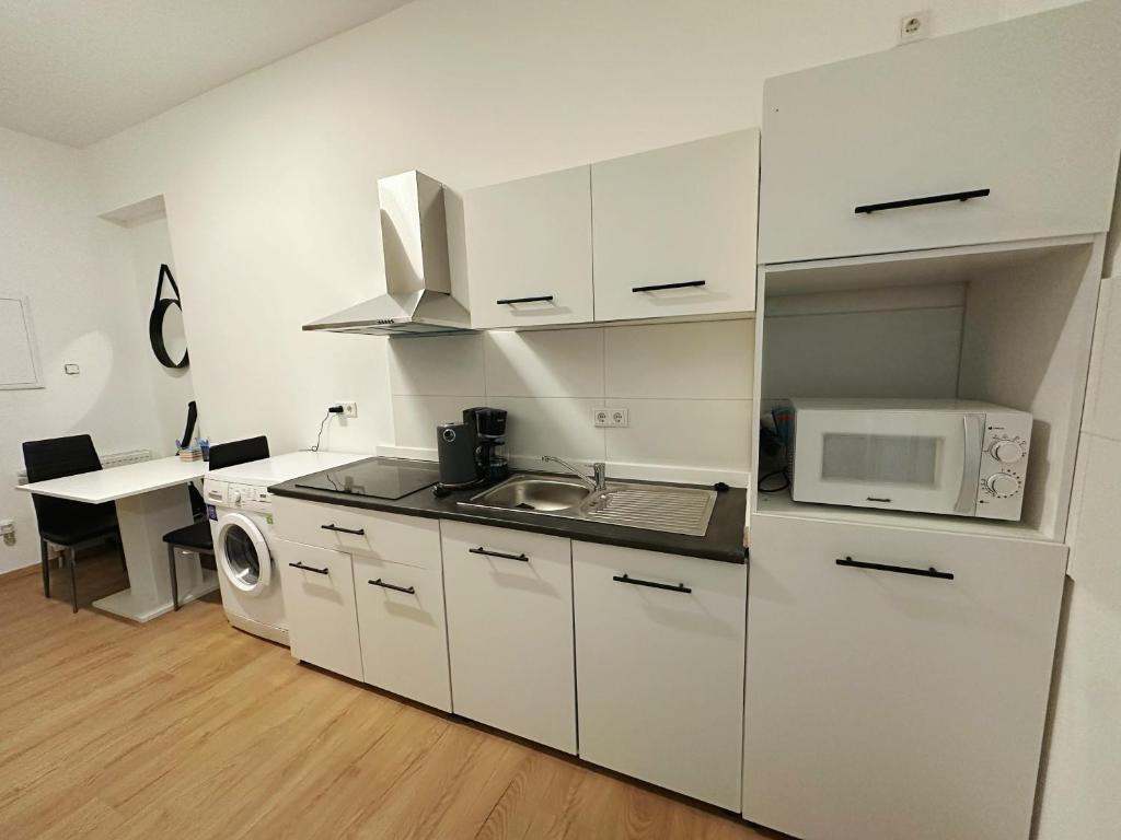 杜塞尔多夫2 schlafenzimmer Waschmaschine Eller的白色的厨房配有水槽和微波炉